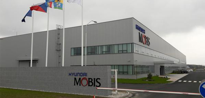 Hyundai Mobis factory building on overcast day, with multiple flags at partial visible.