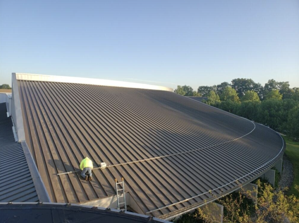 Two workers at the top of a roof with steep slopes.